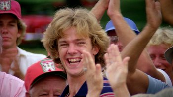 Movie still from “Caddyshack” (1980), directed by Harold Ramis – A young man smiling and clapping with his hands in the air; Close Up shot, Low angle
