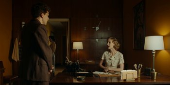 Movie still from “Café Society” (2016), directed by Woody Allen – A man and a woman are sitting at a desk; Medium shot, Over the shoulder angle