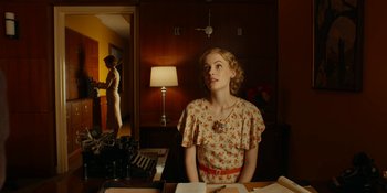 Movie still from “Café Society” (2016), directed by Woody Allen – A woman sitting at a table in a room; Medium shot, Over the shoulder angle