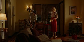 Movie still from “Café Society” (2016), directed by Woody Allen – A man and a woman standing in front of a couch; Wide shot, Low angle
