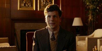 Movie still from “Café Society” (2016), directed by Woody Allen – A man in a suit and tie sitting in front of a fireplace; Close Up shot, Low angle
