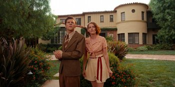 Movie still from “Café Society” (2016), directed by Woody Allen – A man and a woman standing next to each other in front of a house; Wide shot, Low angle
