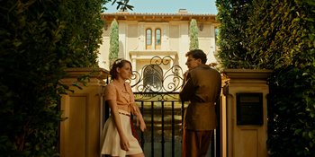 Movie still from “Café Society” (2016), directed by Woody Allen – A man and a woman standing in front of a gate; Wide shot, Low angle