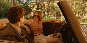 Movie still from “Café Society” (2016), directed by Woody Allen – A woman sitting in the driver's seat of an old fashioned car; Medium shot, Over the shoulder angle