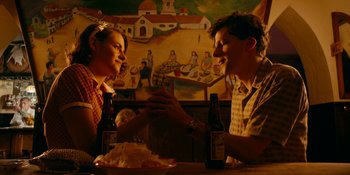 Movie still from “Café Society” (2016), directed by Woody Allen – A man and a woman sitting at a table with beer; Medium shot, Overhead angle