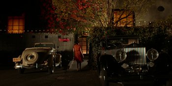 Movie still from “Café Society” (2016), directed by Woody Allen – A woman in an orange dress walking down the street; Extreme Wide shot, High angle
