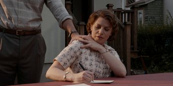 Movie still from “Café Society” (2016), directed by Woody Allen – An older woman sitting at a table writing on a piece of paper; Medium shot, Over the shoulder angle