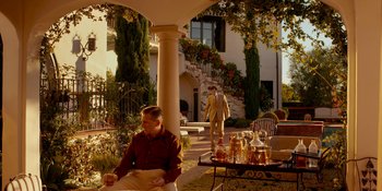 Movie still from “Café Society” (2016), directed by Woody Allen – A man in a suit and tie standing on a porch; Extreme Wide shot, Low angle