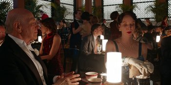 Movie still from “Café Society” (2016), directed by Woody Allen – A group of people sitting at a table with drinks; Medium shot, Over the shoulder angle