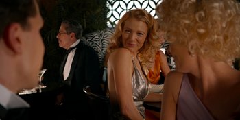 Movie still from “Café Society” (2016), directed by Woody Allen – A woman in a silver dress is smiling at a party; Medium shot, Over the shoulder angle