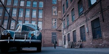 Movie still from “Café Society” (2016), directed by Woody Allen – A man walking down a street next to an old car; Extreme Wide shot, High angle