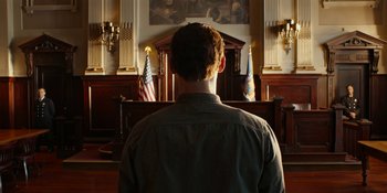 Movie still from “Café Society” (2016), directed by Woody Allen – A man in front of a podium in a courtroom; Medium shot, Low angle