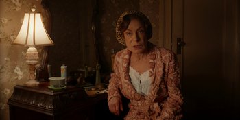 Movie still from “Café Society” (2016), directed by Woody Allen – An older woman wearing a pink dress and a yellow hat; Medium shot, High angle