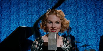 Movie still from “Café Society” (2016), directed by Woody Allen – A woman in a black and white dress holding a microphone; Close Up shot, Low angle