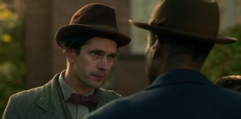 Movie still from “Fargo” (2014), created by Noah Hawley – A man wearing a hat and a bow tie talking to another man wearing a hat and a bow tie; Close Up shot, Over the shoulder angle