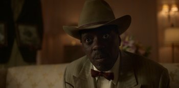 Movie still from “Fargo” (2014), created by Noah Hawley – A man wearing a hat and a bow tie; Close Up shot, Low angle