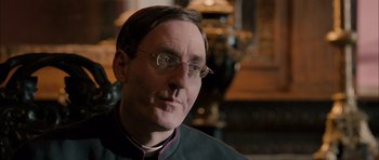Movie still from “Calvary” (2014), directed by John Michael McDonagh – A man wearing glasses and a priest's outfit; Close Up shot, Over the shoulder angle