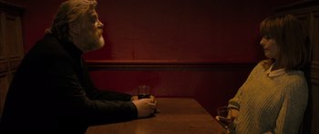 Movie still from “Calvary” (2014), directed by John Michael McDonagh – A man sitting at a table with a glass of wine; Medium shot, Over the shoulder angle