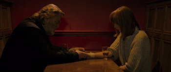 Movie still from “Calvary” (2014), directed by John Michael McDonagh – A man and a woman sitting at a wooden table; Medium shot, High angle