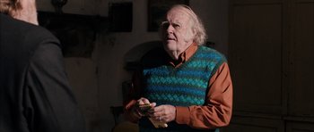 Movie still from “Calvary” (2014), directed by John Michael McDonagh – An older man holding a piece of paper in his hands; Medium shot, Over the shoulder angle