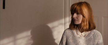 Movie still from “Calvary” (2014), directed by John Michael McDonagh – A woman standing in front of a white wall; Close Up shot, Over the shoulder angle
