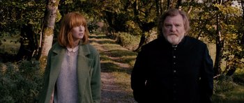 Movie still from “Calvary” (2014), directed by John Michael McDonagh – A man and a woman standing next to each other on a dirt path; Medium shot, Over the shoulder angle