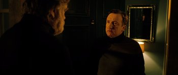 Movie still from “Calvary” (2014), directed by John Michael McDonagh – A man in a black shirt is looking at himself in the mirror; Medium shot, Over the shoulder angle