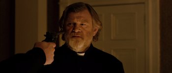 Movie still from “Calvary” (2014), directed by John Michael McDonagh – A man with long hair and a beard holding a gun; Close Up shot, Over the shoulder angle