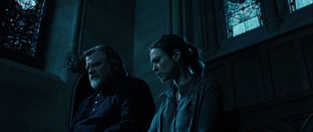 Movie still from “Calvary” (2014), directed by John Michael McDonagh – A man and a woman sitting next to each other in a dark room; Medium shot, Low angle