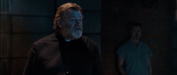 Movie still from “Calvary” (2014), directed by John Michael McDonagh – A man with a beard and a priest's collar; Medium shot, Over the shoulder angle
