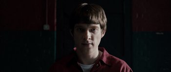 Movie still from “Calvary” (2014), directed by John Michael McDonagh – A young man in a red shirt is staring straight ahead; Close Up shot, Over the shoulder angle