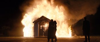 Movie still from “Calvary” (2014), directed by John Michael McDonagh – Two people hug in front of a burning church; Wide shot, Low angle