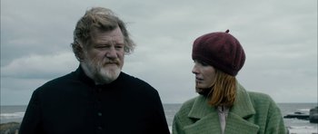 Movie still from “Calvary” (2014), directed by John Michael McDonagh – A man and a woman standing next to each other on the beach; Medium shot, Low angle