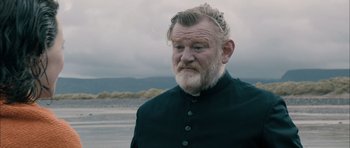 Movie still from “Calvary” (2014), directed by John Michael McDonagh – An old man with a beard and a black jacket; Close Up shot, Over the shoulder angle