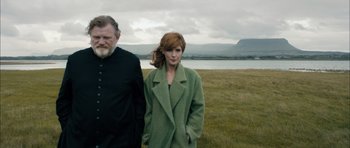 Movie still from “Calvary” (2014), directed by John Michael McDonagh – A woman and a man standing next to each other in a field; Medium shot, Low angle