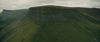 Movie still from “Calvary” (2014), directed by John Michael McDonagh – A green hill with a mountain in the background; Extreme Wide shot, High angle