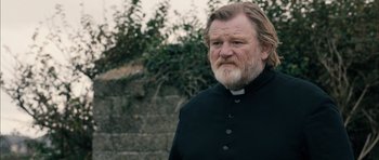 Movie still from “Calvary” (2014), directed by John Michael McDonagh – A man with long hair and a beard wearing a priest's outfit; Close Up shot, Over the shoulder angle