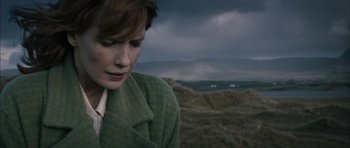Movie still from “Calvary” (2014), directed by John Michael McDonagh – A woman in a green coat looking down at a hill; Close Up shot, Low angle