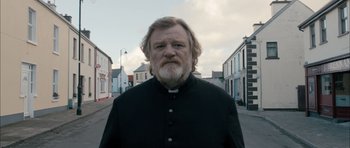 Movie still from “Calvary” (2014), directed by John Michael McDonagh – A man with a beard wearing a priest's outfit; Medium shot, Low angle
