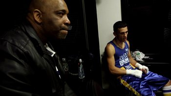 Movie still from “Cameraperson” (2016), directed by Kirsten Johnson – Two men sitting next to each other in a room; Medium shot, High angle