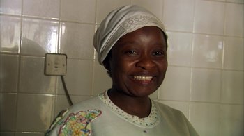 Movie still from “Cameraperson” (2016), directed by Kirsten Johnson – A woman wearing a head covering smiles for the camera; Close Up shot, Low angle