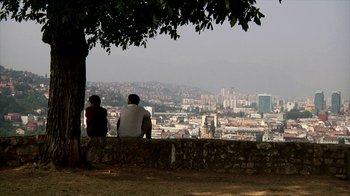 Movie still from “Cameraperson” (2016), directed by Kirsten Johnson – Two people sitting on a wall looking out over a city; Extreme Wide shot, Over the shoulder angle