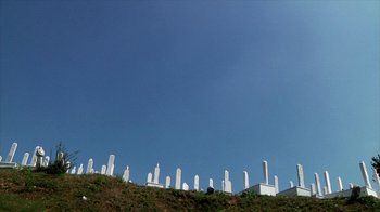 Movie still from “Cameraperson” (2016), directed by Kirsten Johnson – A cemetery on top of a hill under a clear blue sky; Extreme Wide shot, Low angle