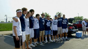 Movie still from “Cameraperson” (2016), directed by Kirsten Johnson – A group of young men standing next to each other on a street; Wide shot, High angle
