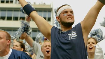 Movie still from “Cameraperson” (2016), directed by Kirsten Johnson – A group of people that are standing in a stadium; Medium shot, Overhead angle