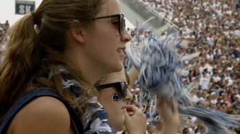 Movie still from “Cameraperson” (2016), directed by Kirsten Johnson – Two women are sitting in the bleachers at a football game; Close Up shot, High angle