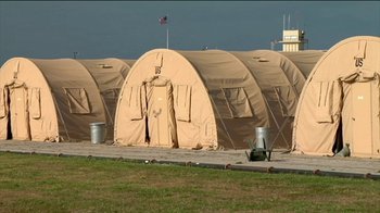 Movie still from “Cameraperson” (2016), directed by Kirsten Johnson – A group of tents that have been set up in a field; Extreme Wide shot, Low angle