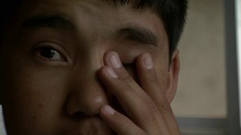 Movie still from “Cameraperson” (2016), directed by Kirsten Johnson – A person holding his hand to his face; Extreme Close Up shot, High angle