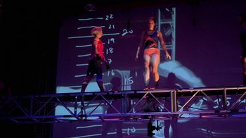 Movie still from “Cameraperson” (2016), directed by Kirsten Johnson – A couple of women standing next to each other on top of a stage; Wide shot, Low angle