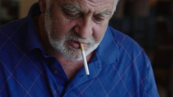 Movie still from “Cameraperson” (2016), directed by Kirsten Johnson – An older man with a cigarette in his mouth; Close Up shot, Low angle